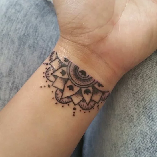 kleines Tattoo mit halber Sonne im indischen Stil am Handgelenk