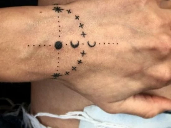 kleines Tattoo mit Sternen und Mond am Handgelenk