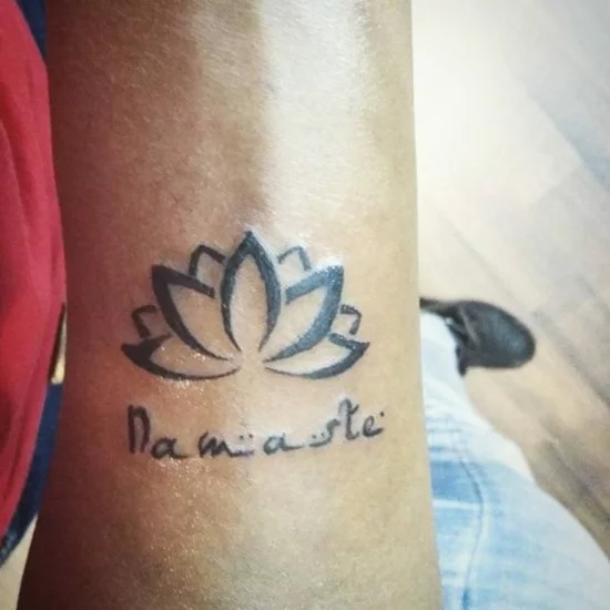 Blackwork Tattoo mit Namaste Schriftzug und Lotus