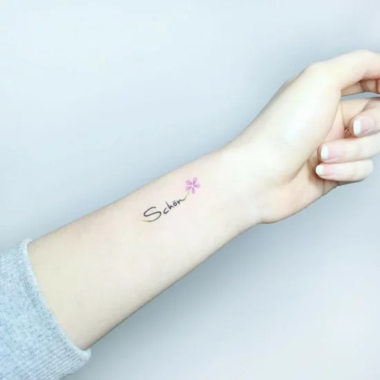 zierliches Tattoo am Handgelenk mit Schrift und Blume
