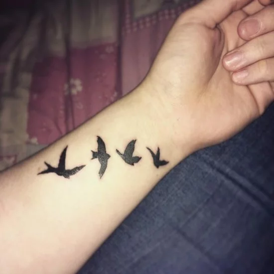 Vogelschar Tattoo in Blackwork am Handgelenk