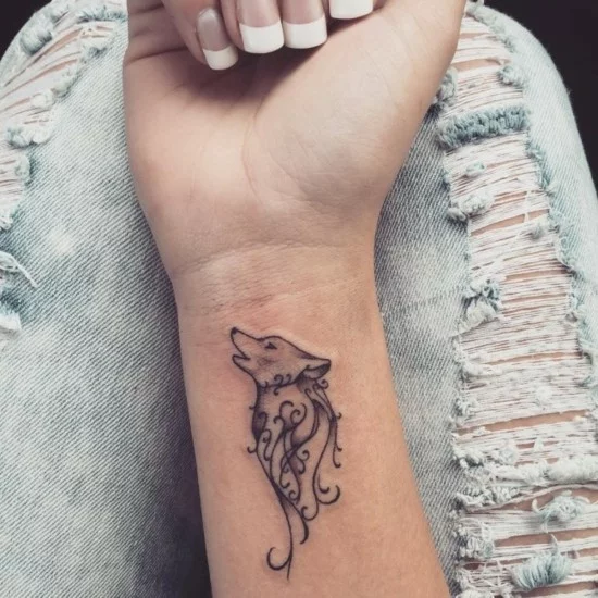 Wölfin als Tattoo am Handgelenk einer Frau