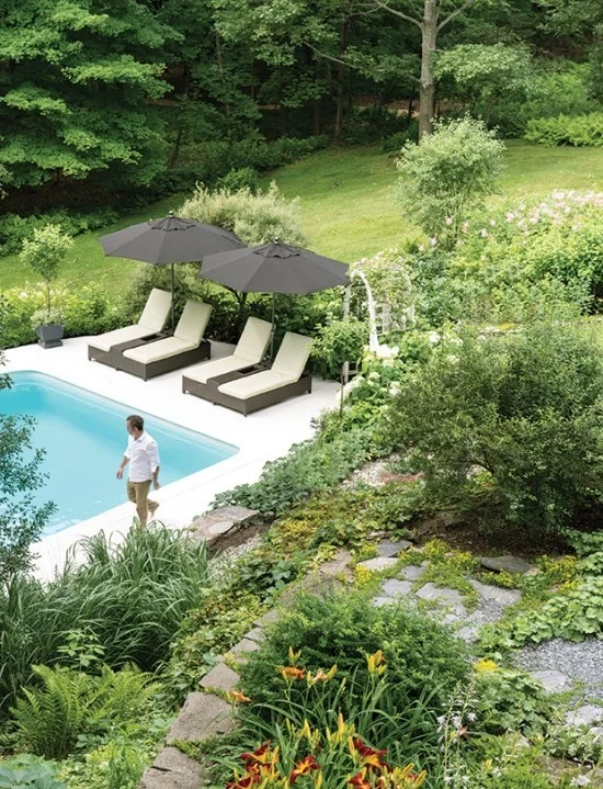 beste Ideen für Pool im Garten moderne weiße Sonnenliegen schwarze Sonnenschirme viel Grün 