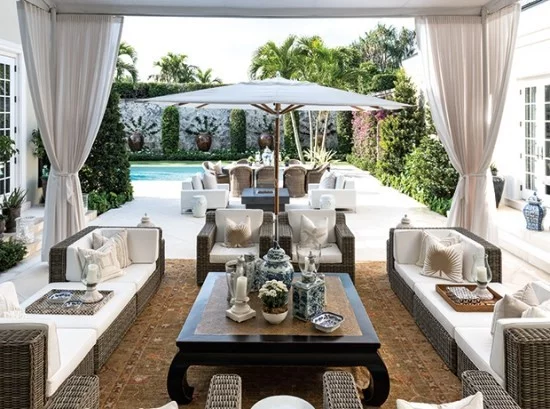 stilvolle Outdoor Gestalung Relax Zone Schirm Gardinen weiße Sofas braune Bodenfliesen 