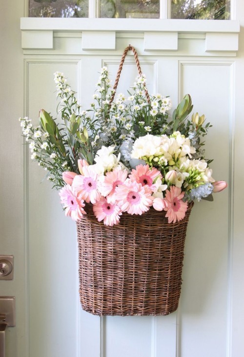 Weidenkorb voller schöner Blumen an der Tür