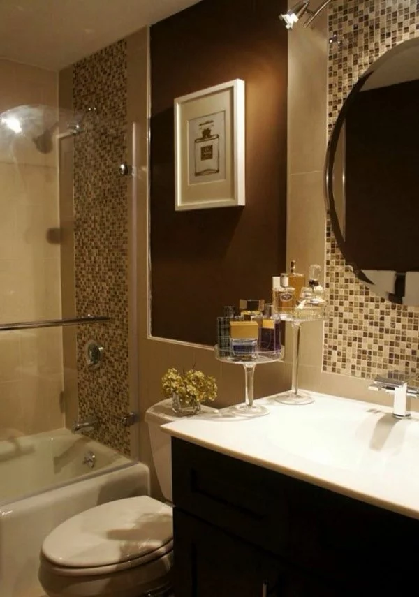 kleines Badezimmer mit Mosaikfliesen, rundem Wandspiegel und brauner Akzentwand