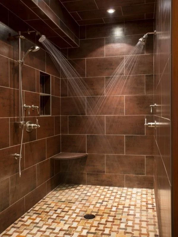 Dusche mit großen braunen Wandfliesen und kleinen Bodenfliesen mit einem kreativen Design