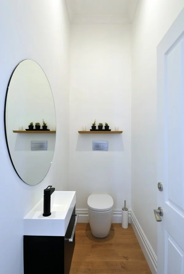 runder badspiegel schlichtes baddesign weiße wände bodenbelag holzoptik
