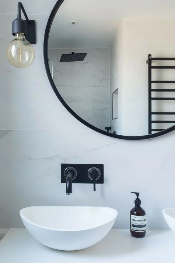 runder badspiegel weiße badezimmerwände schwarze akzente