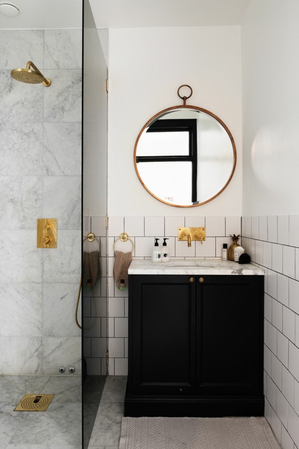 runder badspiegelb schwarzer waschbeckenunterschrank weiße badezimmerfliesen