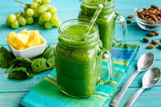 Weckglasbecher gefüllt mit grünem Spinat-Kohl Getränk Trauben grüne Smoothies blaue gestreifte Serviette