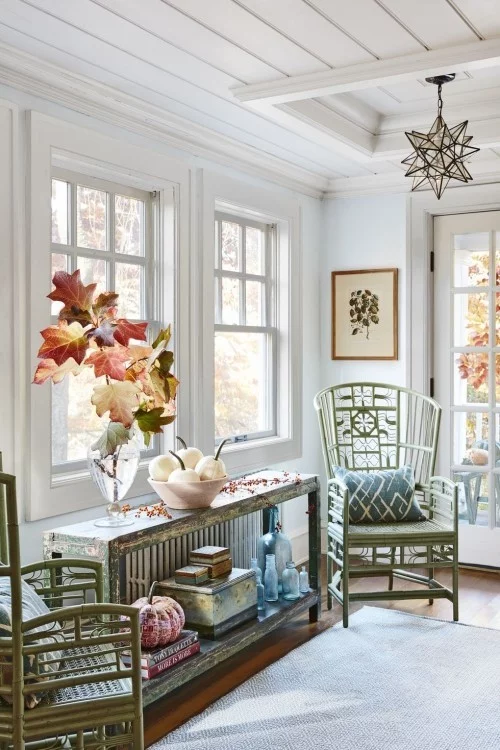 warme Farben ins Interieur bringen - eine Vase mit großen Herbstblättern und Kürbisse daneben