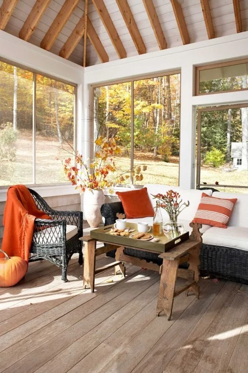 Wohnzimmer auf der verglasten Veranda in warmen Herbstfarben 