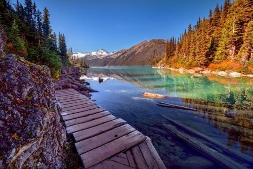 Kanada bereisen Holzbrücke Blick auf Gletschersee Kieferwald naheliegende Berge