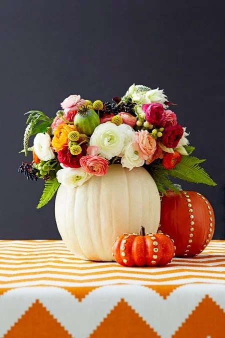 Ausgehöhlte Kürbisse als Vasen voll mit Herbstblumen Tischdeko im Herbst