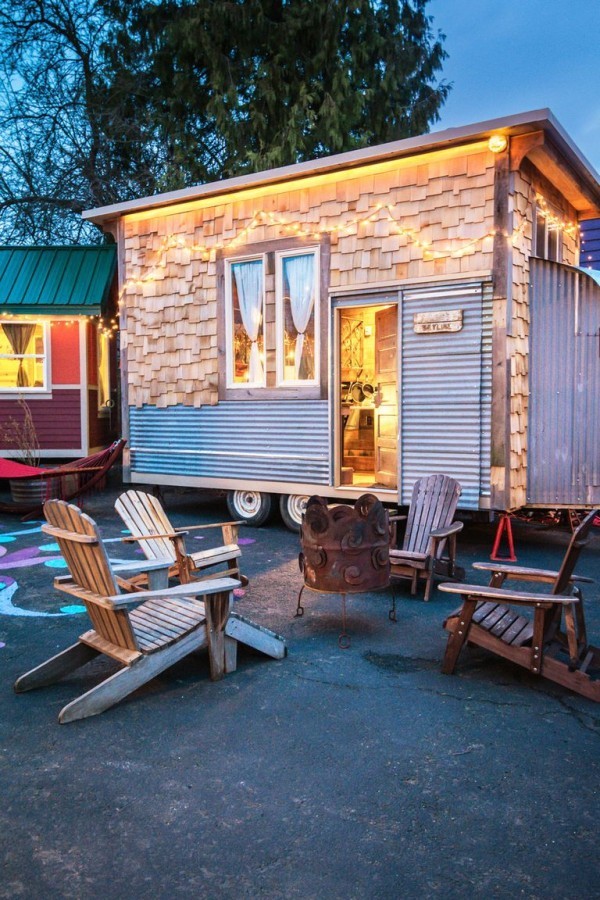 Tiny Houses ein kleines Haus aus Metall und Holz auf Rädern mit Sitzecke im Freien