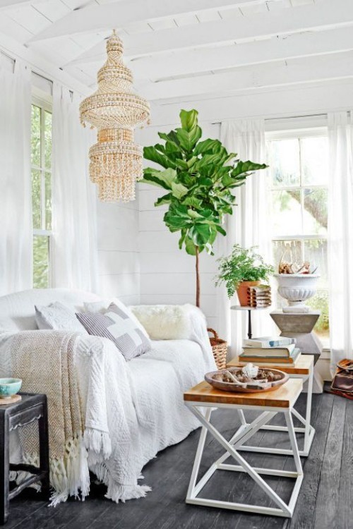 Wohnzimmer im Landhausstil weiße Couch Zimmerpflanzen alter Kronleuchter Klapptische