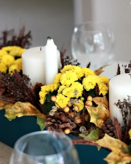 gelbe Chrysanthemen weiße Kerzen Tannenzapfen Tischdeko im Herbst