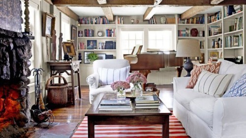 gemütliches Wohnzimmer im Landhausstil viel Holz weiße Möbel gestreifter Teppich Balken Bücherwand