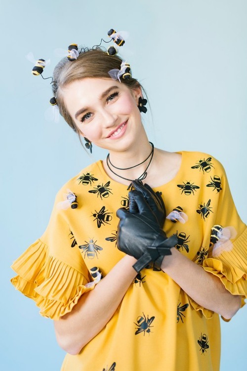 Lustige Halloween Kostüme als eine Biene gelbes Kleid gemustert mit schwarzen Handschuhen
