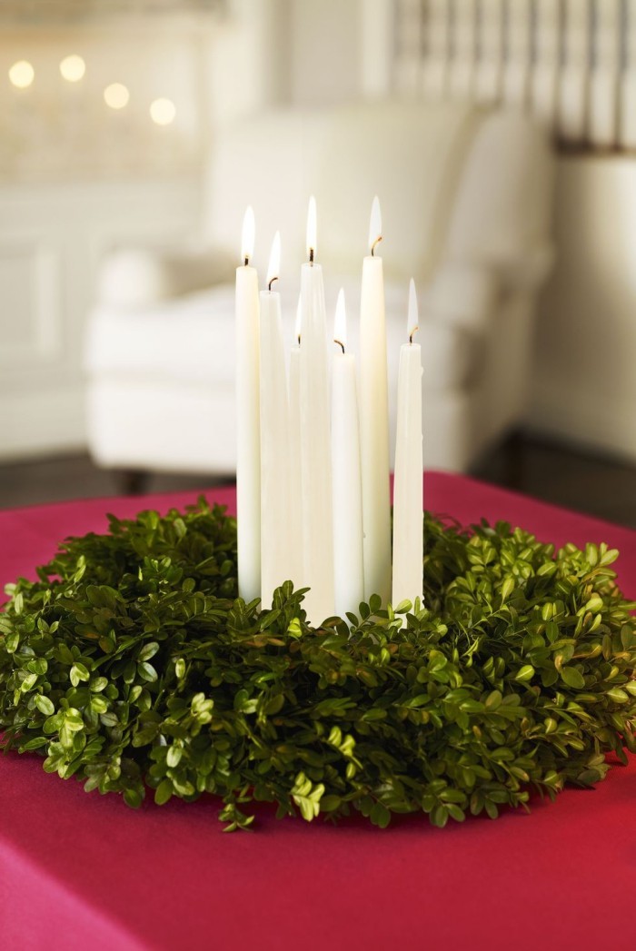 Tischdeko Ideen zu Weihnachten Kranz binden aus grünen Efeuzweigen brennende weiße Kerzen