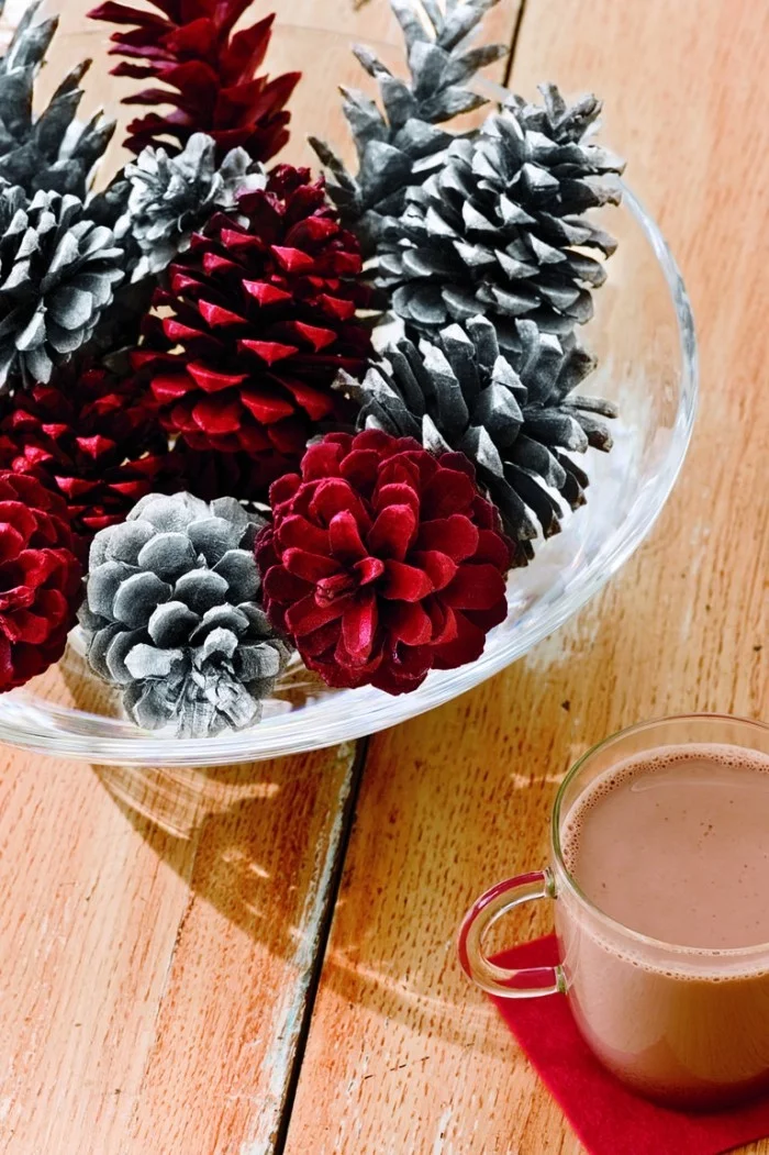 Tischdeko Ideen zu Weihnachten Zapfen in verschiedenen Farben bemalt in einer Schüssel zentral arrangiert Tasse heißer Kakao