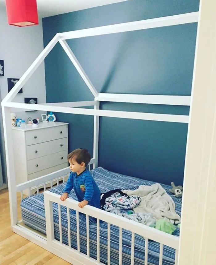 Montessori Bett in Weiü mit gestreifter Matratze und vor blauer Wand