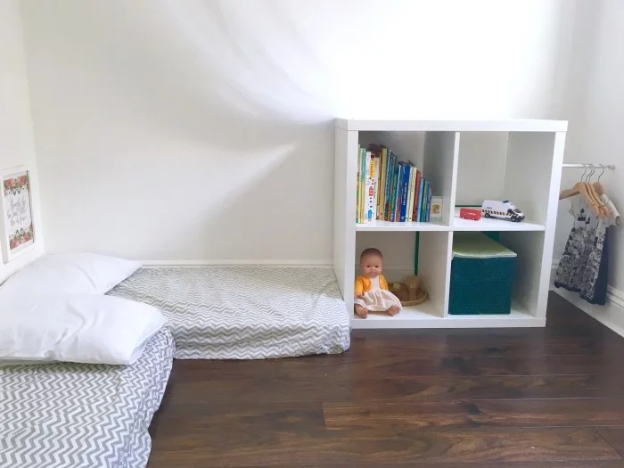 Zwei unterschiedlich positionierte Montessori Betten im Kinderzimmer mt dunklem Fußboden 