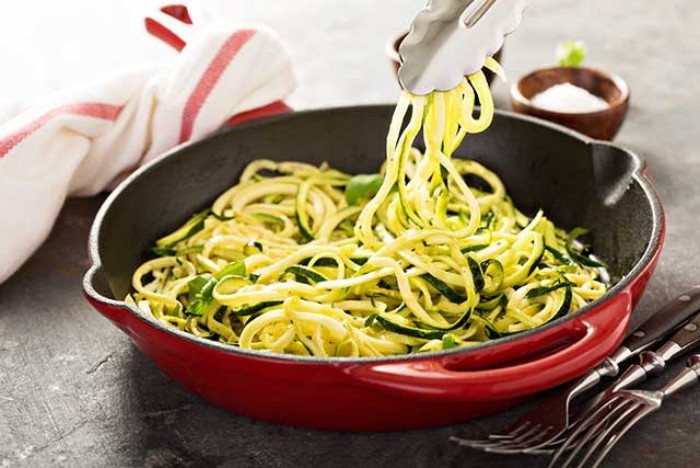 Essen ohne Kohlenhydrate Zucchini wie Nudeln in der Pfanne anbraten mit Basilikum Blättern servieren