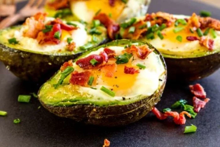 Essen ohne Kohlenhydrate das perfekte Frühstück halbierte Avocado mit Ei und Speck überbacken
