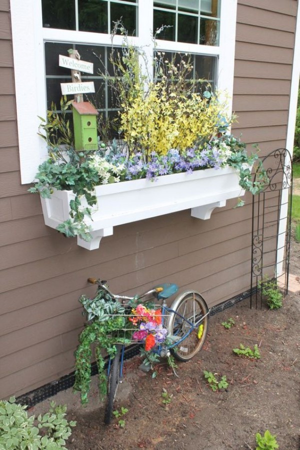 Blumenkasten an der Fensterbank weiß üppig bepflanzt Vogelhaus Kinderfahrrad darunter