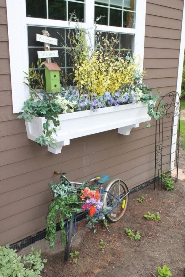Blumenkasten an der Fensterbank weiß üppig bepflanzt Vogelhaus Kinderfahrrad darunter
