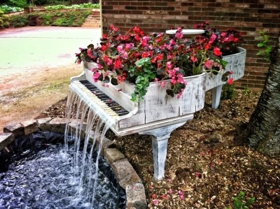 altes Klavier als Blumenbeet und Brunnen im Garten 
