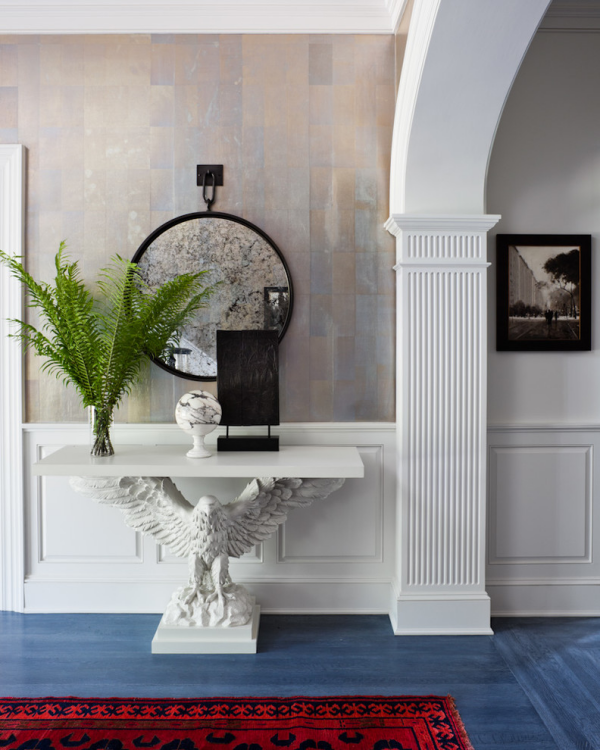 Dekorative Wandspiegel im Flur klassisches Design Adlerfigur als Tischbein weißer Tisch Farn runde Spiegelform