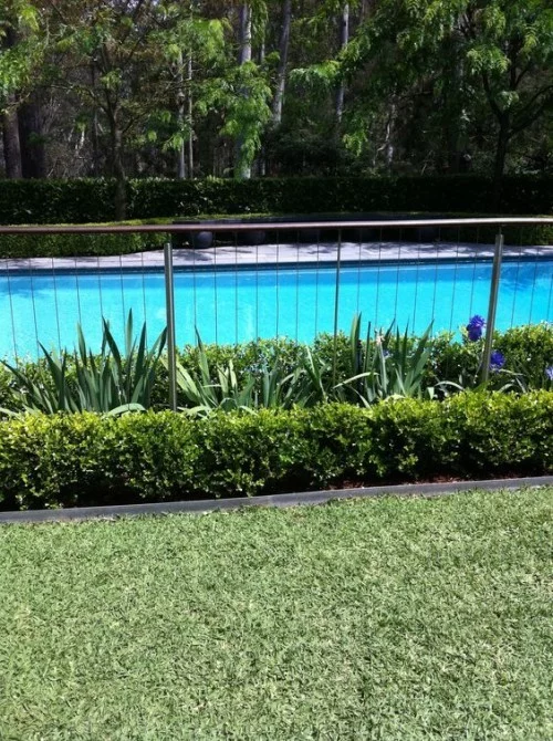Zaun um Pool Ideen aus Metall mit zahlreichen Grünpflanzen
