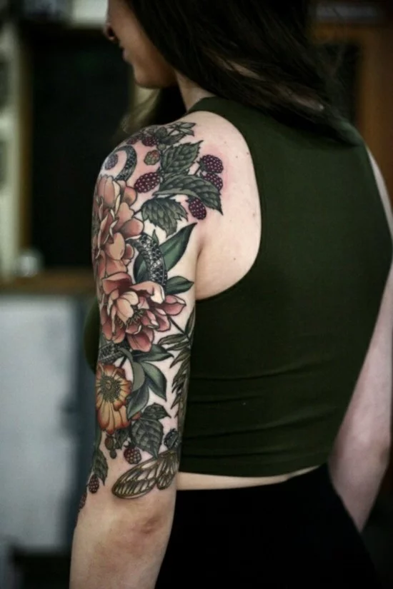 Oberarm Tattoo mit viele Blumen und Brombeeren 