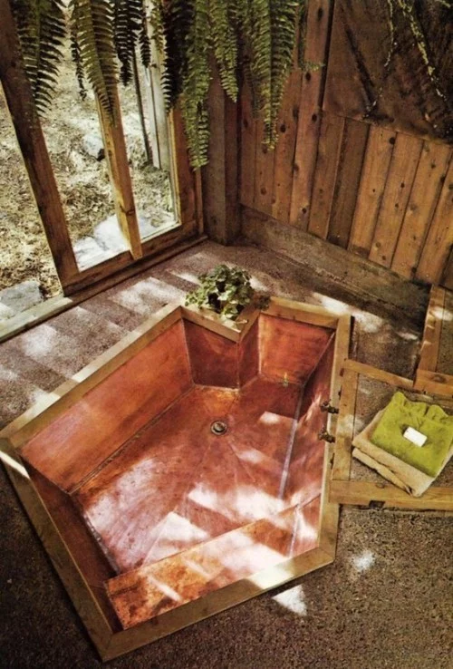 Eingelassene Badewanne mehreckige Form Holzwand grüne Pflanzen Farne