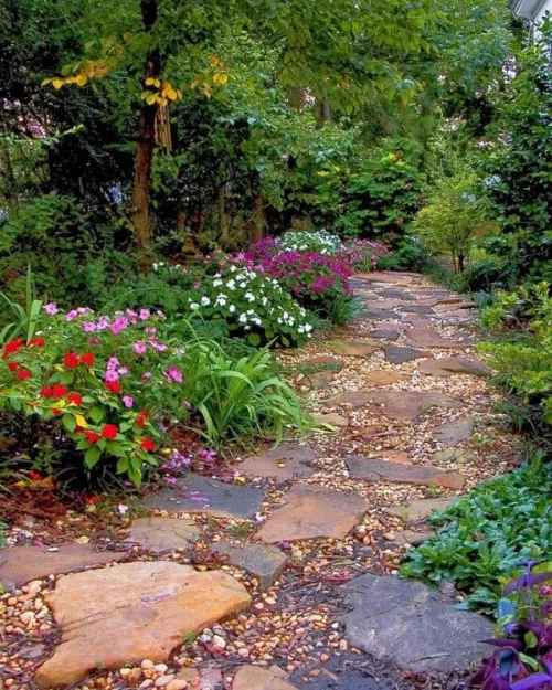 Gartenwege aus Stein große Steinplatten Kies viele bunte Blumen beiderseits