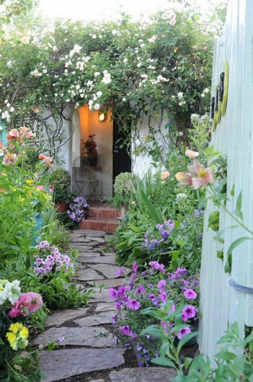 Gartenwege aus Stein mit Steinplatten belegt von Sonnenblumen umgeben führt direkt zum Hauseingang
