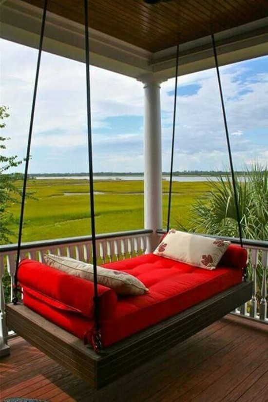 Hängebett draußen auf der überdachten Terrasse rote Polsterung zwei Deko Kissen herrlicher Panoramablick auf die grüne Landschaft