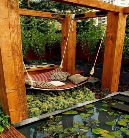 Hängebett draußen ausgefallenes Design im japanischen Stil direkt am Teich viele grüne Pflanzen Deko Kissen