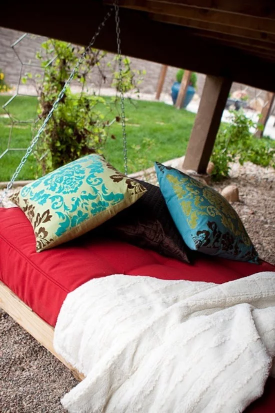 Hängebett draußen bunte Kissen als Deko grüner Garten im Hintergrund