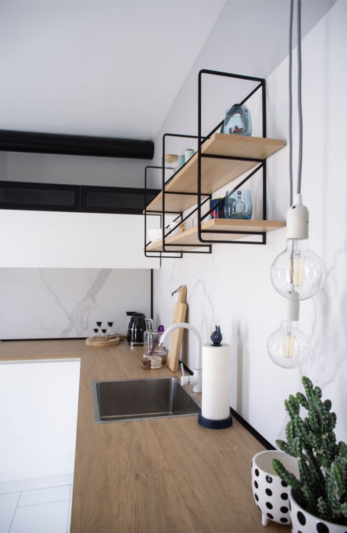 Kleines Apartment einrichten L-Form-Küche minimalistisch gestaltet weiße Wände offenes Regal Arbeitsplatten aus Holz Spüle Kakteen im Topf