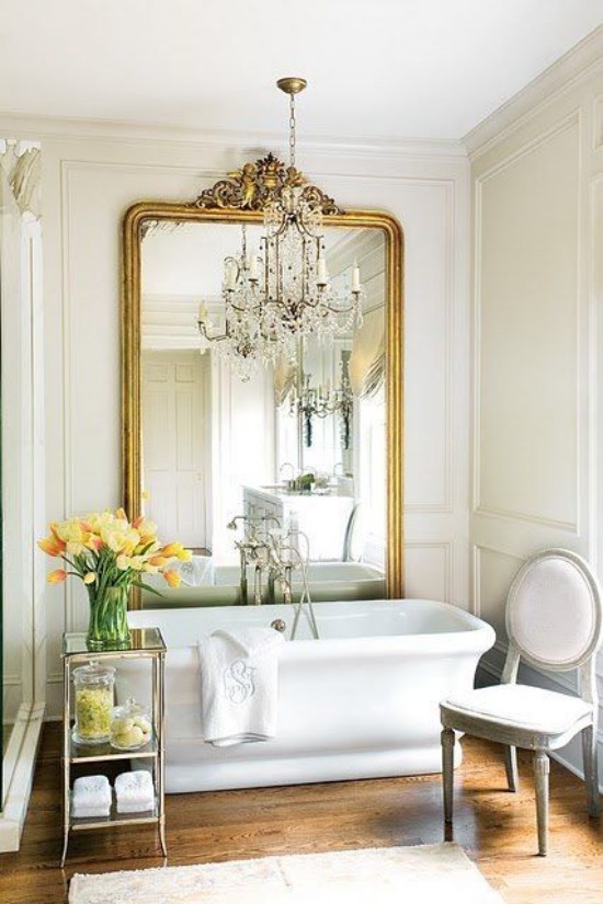 Pariser Chic im Bad moderne Badewanne großer Wandspiegel verzierter Rahmen Beistelltisch Blumen Kronleuchter Stuhl