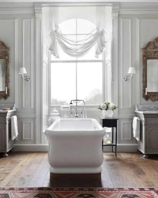 Pariser Chic im Bad sehr ansprechende Atmosphäre freistehende Badewanne großes Fenster drapierte Gardinen große Wandspiegel Teppich weiße Blumen