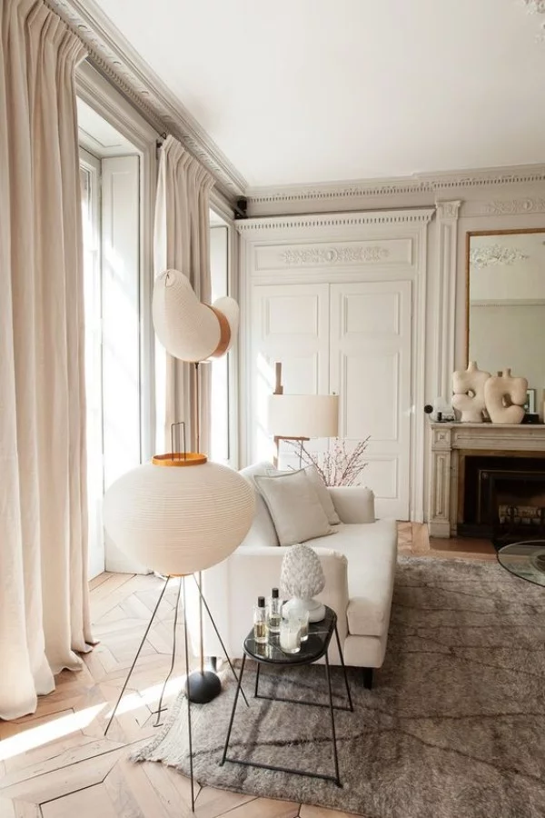 Pariser Chic im Wohnzimmer weiße Wände hellgrauer Teppich weißes Sofa Lampe Kamin Spiegel Deko Artikel