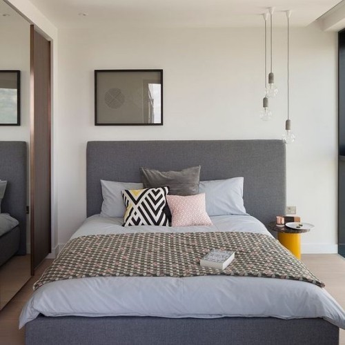 Asymmetrie im Interieur grau gestaltetes Schlafzimmer hängende Elektrobirnen recht Wandspiegel links Schlafbett