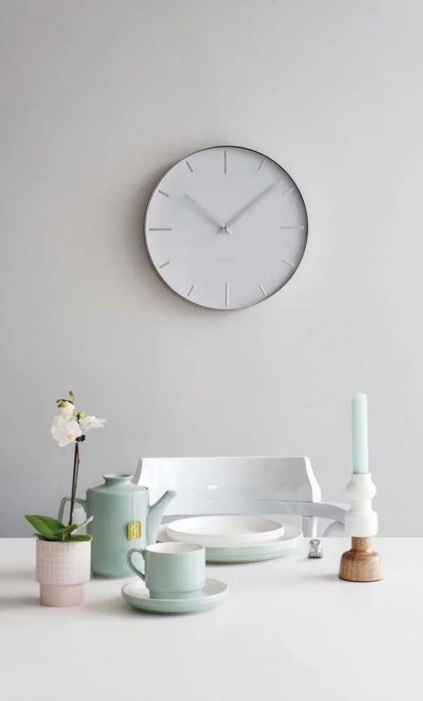 Eine weiße Wanduhr mit Geschirr auf dem Tisch