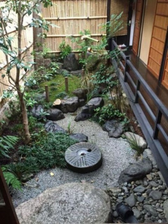 Japanischer Garten im Hinterhof Bambuswand Steine Moos Kies grüne Pflanzen niedriger Zaun