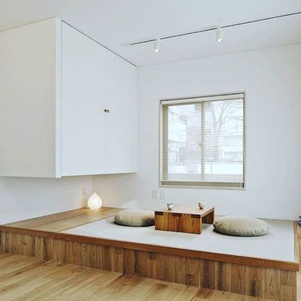 Japanisches Wohnzimmer reduzierte Ästhetik niedriger Tisch zwei Bodenkissen weiße Wände